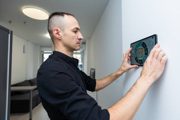 automation, internet of things and technology concept - man looking at tablet pc computer at smart home