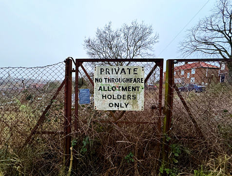 Sign on an overgrown gate at an allotment in Norwich