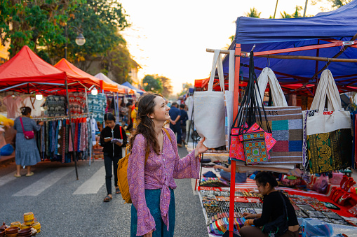 Woman exploring street  market in Luang Prabang during her vacation to Southeast Asia