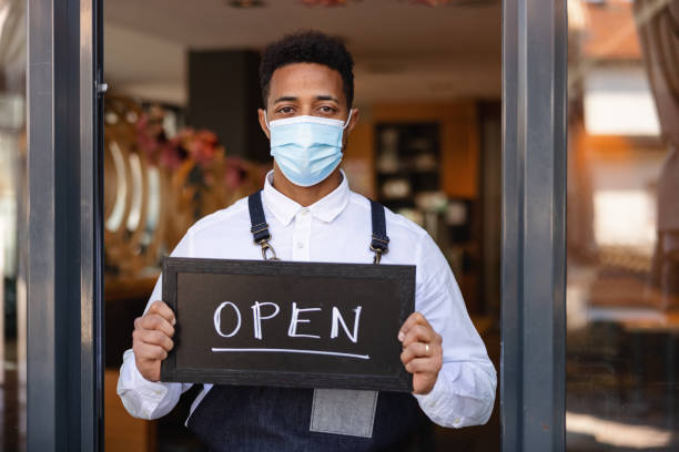 istock Mixed Race Waiter Holding An Open Sign In A Cafe 1959656505