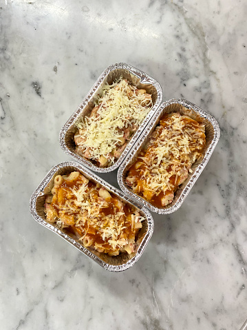 Cheesy Scotel Macaroni Baked Creamy in aluminum  foil container on the table