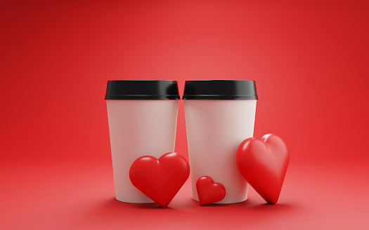 Two white disposable cups for coffee and tea stand next to red hearts on a red background. Valentine`s Day concept.