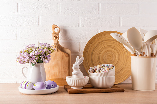 Easter holiday decorations on a wooden kitchen countertop with eco-friendly kitchen utensils and eggs, ceramic bunnies . Easter concept