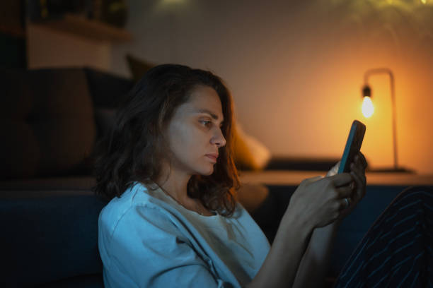 istock Young woman looking at smartphone screen while sitting at home in the evening 1959691218
