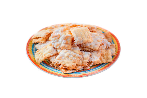 istock Traditional sweet crisp pastry deep-fried and sprinkled with powdered sugar on multicolored plates isolated on white. Carnival food tradition. 1959707710