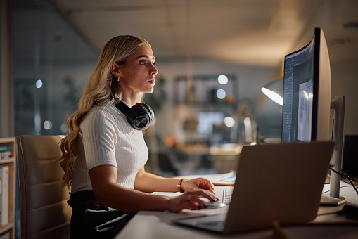 Woman, night and graphic designer with computer and project deadline, creativity and concentration at desk. Technology, web design and internet with productivity, creator working late at SEO startup