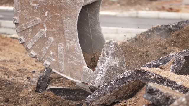 Excavator scooping asphalt