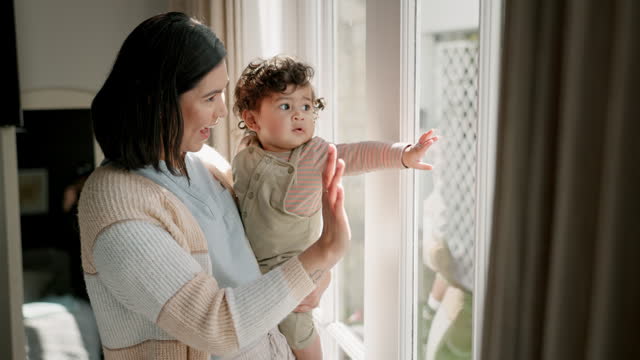Window, home and mother wave with baby looking at garden view for bonding, love and relaxing. Family, glass and happy mom with child pointing outdoors for connection, development and childhood