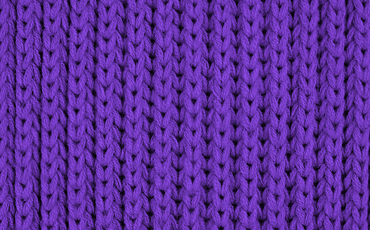 Texture of knitted wool fabric with of a lilac color with pattern. Top view. Close-up. Selective focus.