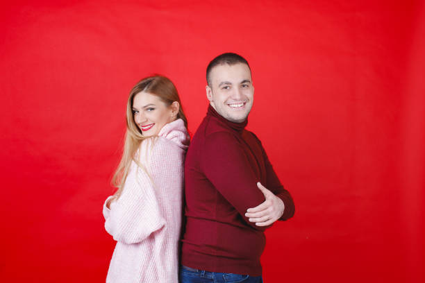 istock Young couple in turtleneck sweaters standing back to back and smiling at camera 1959808698