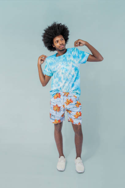 istock Tropical Elegance: Afro Man in Bermuda Shorts and Tee on Green 1959820536
