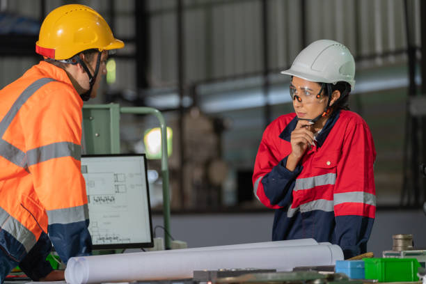 Innovation as a dynamic group of engineers gathers around a table in a factory for a strategic meeting on an exciting factory expansion project. Collaboration, expertise, and forward-thinking within the industrial realm.