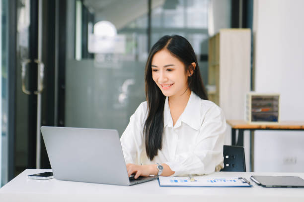 istock Young Asian businesswoman working with working notepad, tablet and laptop documents talking on the smartphone, tablet and laptop video call 1959832150