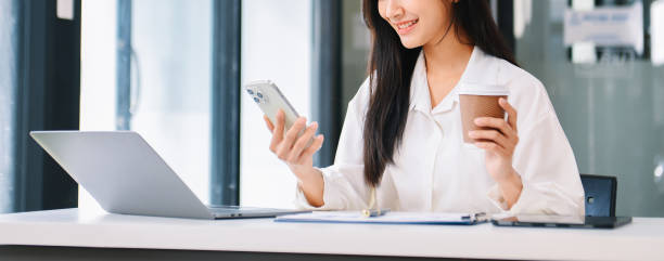 istock Young Asian businesswoman working with working notepad, tablet and laptop documents talking on the smartphone, tablet and laptop video call 1959832681