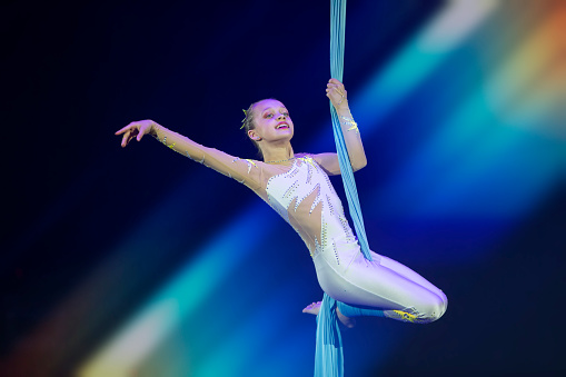 Performance by a circus acrobat artist. Girls perform aerial acrobatic elements on fabric.