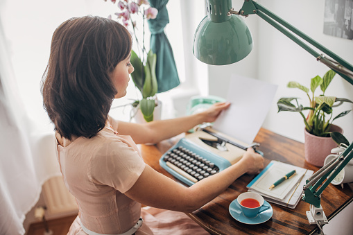 Classy young woman typing on a typewriter in her apartment.