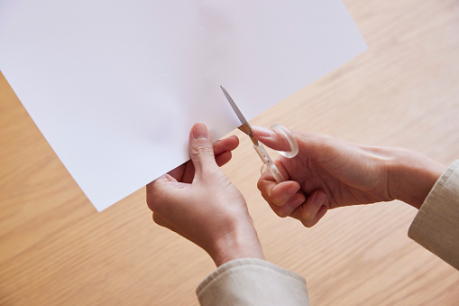 Hand of a woman cutting paper with scissors