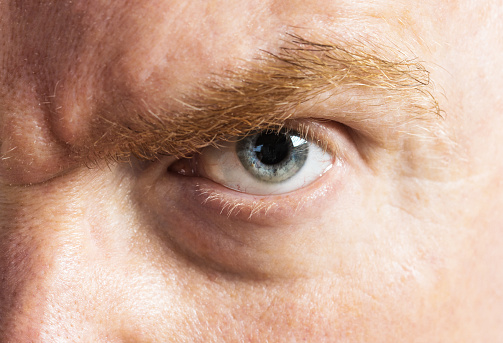 Scary glaring man's eye in close-up, with copy space on his cheek.