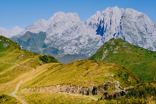 The majestic Carnic Alps' awe-inspiring peaks stand nearby, with hiking paths meandering through the forefront mountainside. This composition blends blue and green hues, crafting a breathtaking alpine panorama of alpine tranquillity.