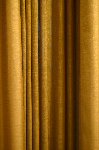 Bright rust or bronze brown coloured textured fabric pleated curtains that has curled up simple and elegant retro style vintage classic squiggled ribbed pleats making a wallpaper or background