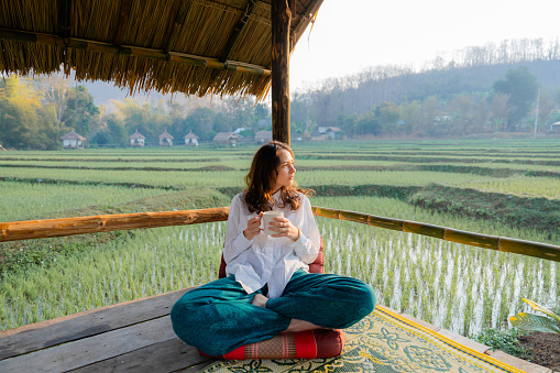 Serene woman drinking tea enjoying the view on rice terraces  in the morning