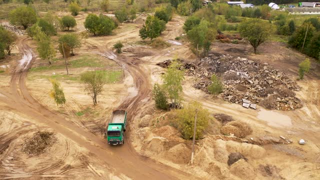 Drone footage of new construction waste dump site and dump truck driving during autumn cloudy day