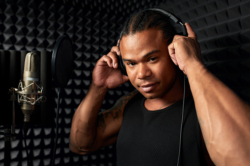 African American at the recording studio in headphones reads rap.