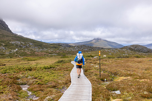 Amidst the captivating landscapes of Tasmania, a lone adventurer embarks on a long-distance walk, weaving through the untamed beauty of the wilderness. Each step tells a story of resilience and exploration as he navigates diverse terrains, from dense forests to open valleys. The air is crisp, carrying the essence of nature's purity. Against the backdrop of towering mountains and sprawling vistas, the man's silhouette paints a picture of determination and awe-inspired wanderlust. This is a journey etched with the footprints of solitude and the breathtaking beauty of Tasmania's unspoiled terrain.