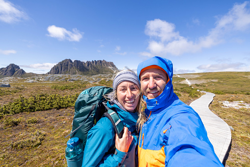 Embarking on an enchanting trek through Tasmania's picturesque landscapes, a couple forges a path together through the wilderness. Amidst towering trees and breathtaking vistas, they pause to capture a cherished moment—a selfie that encapsulates the joy of their shared journey. Against the backdrop of untamed beauty, their smiles tell a tale of adventure, love, and the serenity found in the heart of Tasmania's natural wonders.