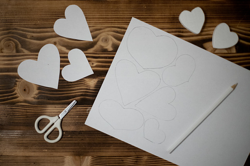 Hand-carved diy hearts made of white copy paper. Preparation for crafts for Valentine's Day. Gift ideas for Valentines Day, day love, concept of February 14. Step by step. process crafts. Valentine card.