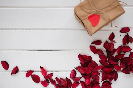 Red rose petals and gift on wood