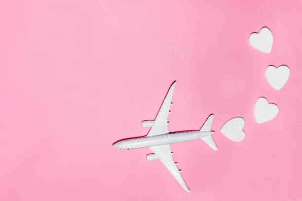 istock Happy Valentine's Day. White passenger plane with hearts on pink background. Flat lay vacation planing and traveling holiday. Holiday travel concept. Top view 1959964072