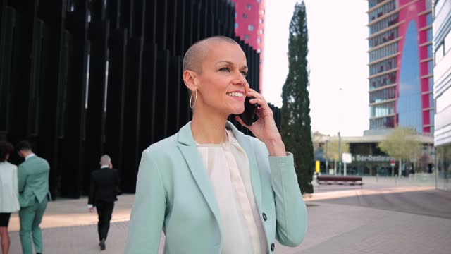 Slow motion. Successful business woman with suit alking and talking by mobile phone. Businesswoman having a call conversation on a cellphone. Executive female chatting using a smartphone at workplace.