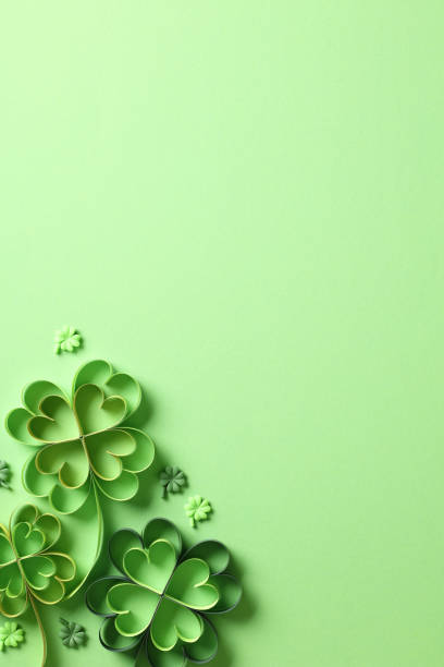 istock St Patrick Day concept. Paper art and craft style four-leaf clover on green background. Flat lay, top view, vertical. 1959990205