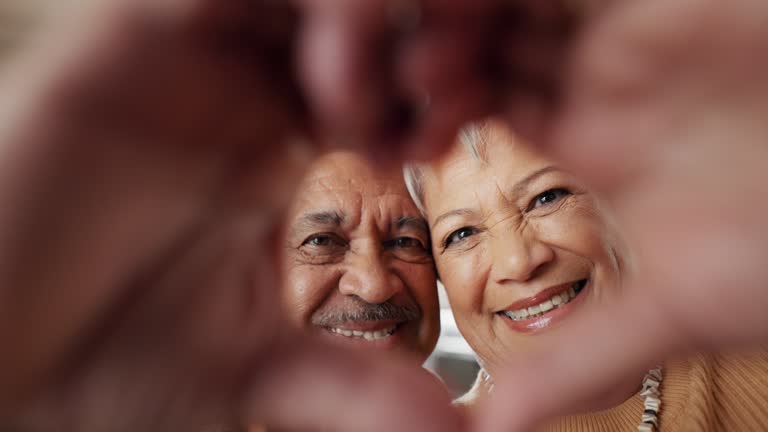 Happy, selfie and senior couple in a living room with heart, hands or frame zoom in their home together. Smile, portrait and elderly people bond in retirement with profile picture, memory or love