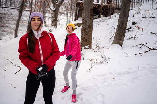 Young female couple running together in a park on a snowy day