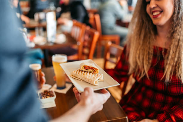 Young woman being served a tortilla wrap by a waiter in the pub.
