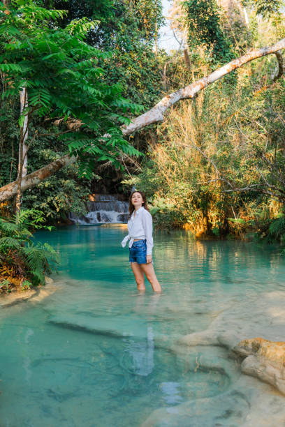 istock Woman enjoys refreshing  waterfall in tropical forest 1960024937