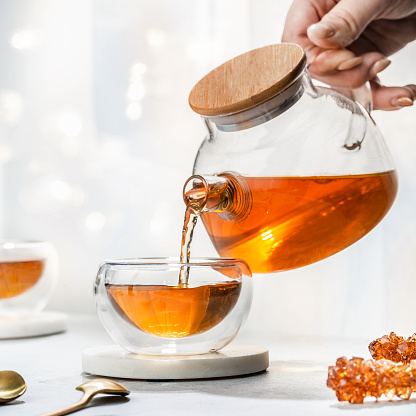 tea concept, tea is pouring into a cup, on white background. Brewing and Drinking tea.