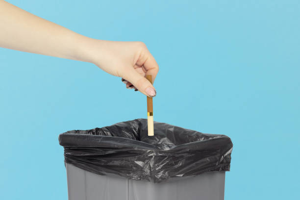 istock throw a cigarette in the trash bin, cigarette in hand in front of the trash bin, smoking cessation concept 1960046078