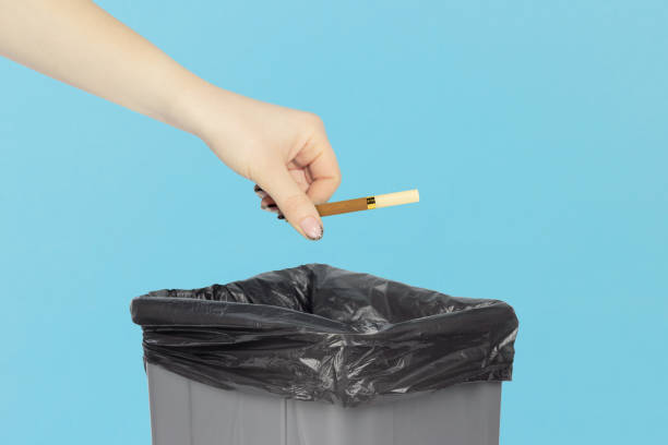istock throw a cigarette in the trash bin, cigarette in hand in front of the trash bin, smoking cessation concept 1960046082