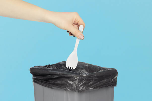 istock throw a plastic fork into the trash, disposable fork in hand in front of a trash can, plastic recycling concept 1960047209