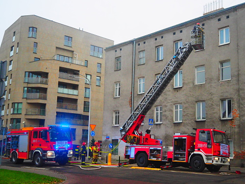 Warsaw, Poland; November 23, 2022: Fire engine and firefighters up on the extended ladder in front of an apartment building