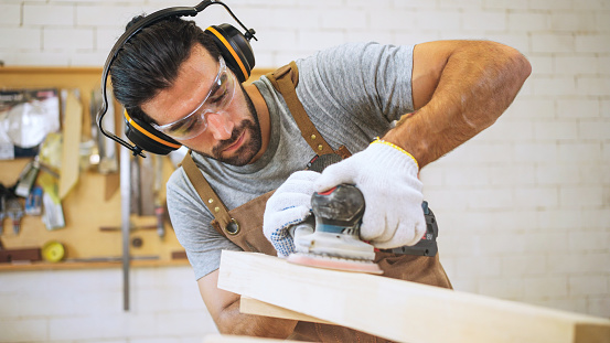 Handsome Carpenter. Small Business Owners of a Furniture Workshop Using cutting wood for the Design of a New Wooden furniture.