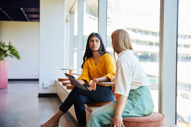 istock Two diverse businesswomen talking over a tablet in an office hallway 1960083812