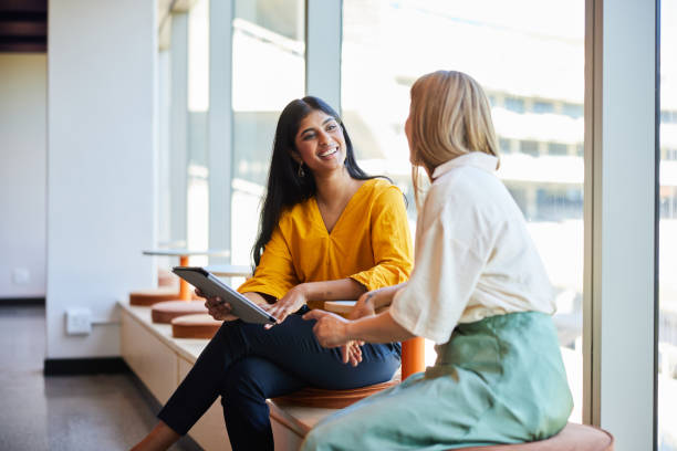 istock Smiling diverse businesswomen talking over a tablet in an office corridor 1960084909