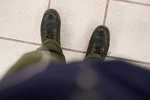 Selfie of male legs in black leather boots and green color pants on the pavement.
Man taking photo of his foots stand on blank floor, top view. Design mock up. A male wear shoes with casual dress and watching down on road street.