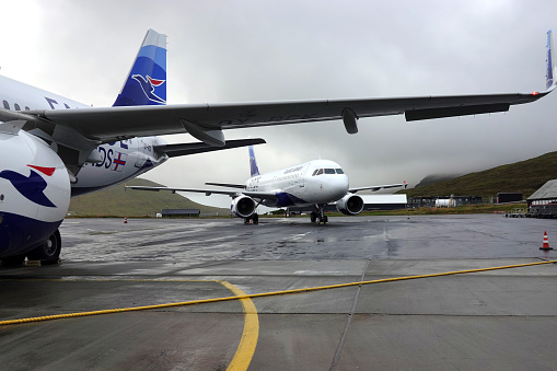 Atlantic Airways airplanes on   the ground on a dramatic cloudy day on Faroe Islands