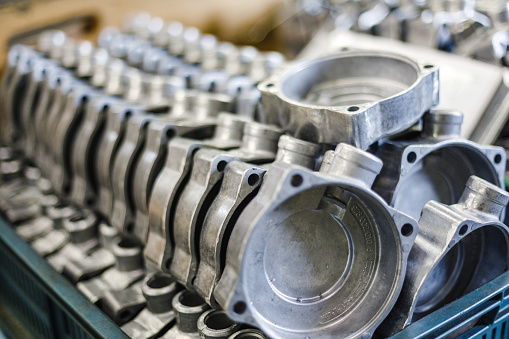 Silver metal casting organized in a plastic blue box in a warehouse. The castings will later be processed by the CNC machine.