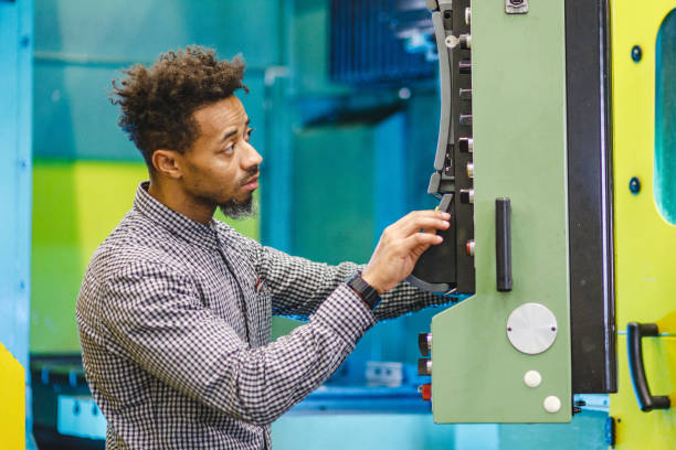 istock Focused Adult Mixed Male Electrical  Engineer Pressing The Buttons On The Control Panel Of A CNC Machine In A Factory 1960127595